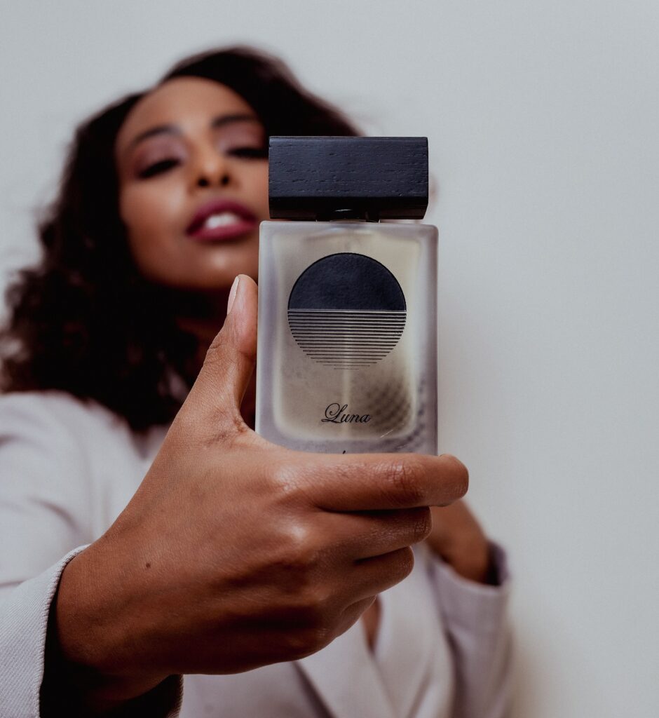Close-up of an African American woman elegantly holding a luxury perfume bottle, highlighting beauty and sophistication.